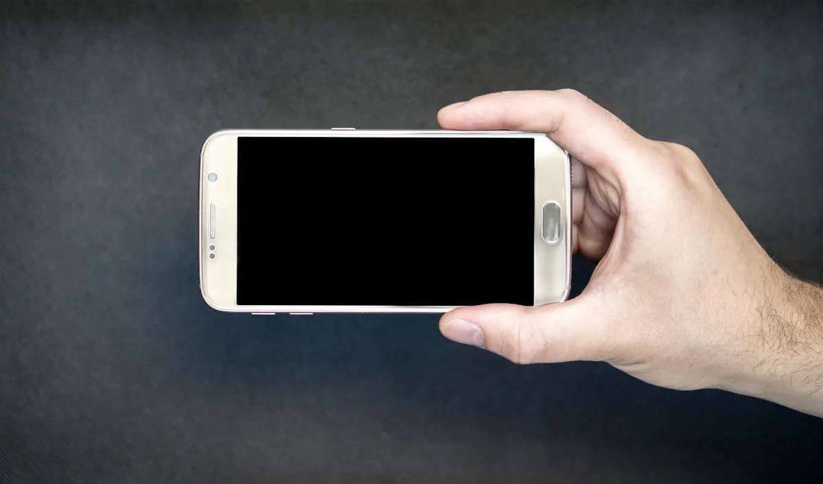 A hand holding a smartphone with a blank screen